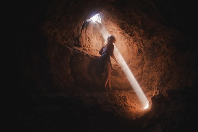 洞窟内に射す光と女性